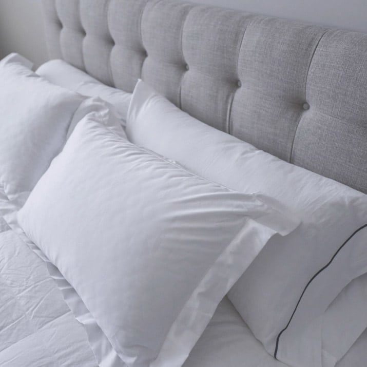 Head of bed with white pillows and headboard